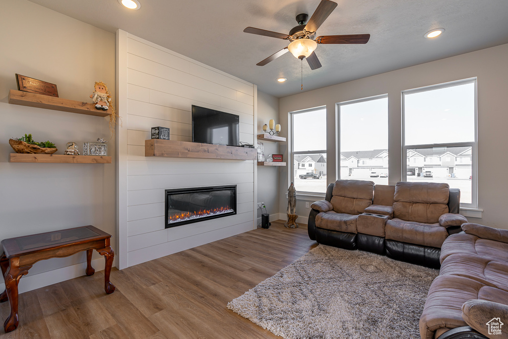 Living area featuring a large fireplace, a ceiling fan, wood finished floors, recessed lighting, and baseboards