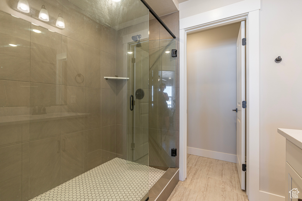 Full bath featuring a shower stall, vanity, baseboards, and wood finished floors