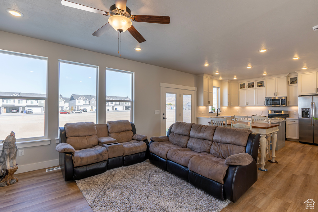 Living area with healthy amount of natural light, light wood-style flooring, a ceiling fan, and recessed lighting