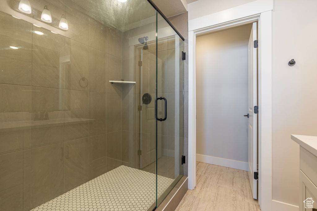 Bathroom featuring a stall shower, vanity, baseboards, and wood finished floors