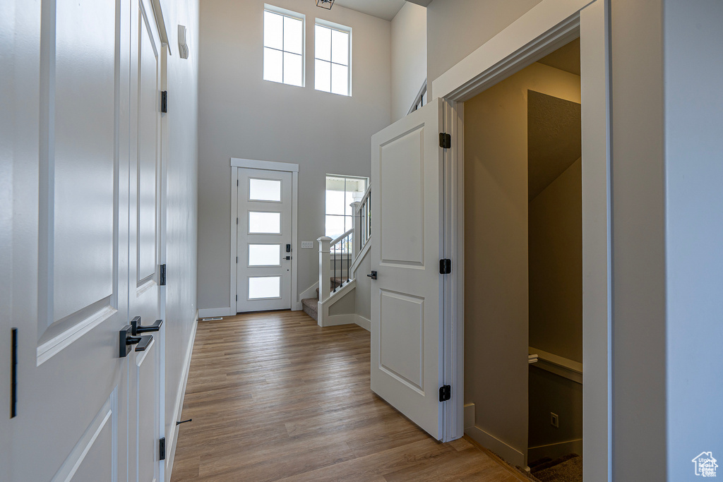 Entrance foyer featuring light wood-style floors, stairway, baseboards, and a high ceiling