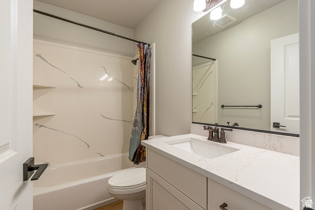 Bathroom with vanity, toilet, and shower / bathtub combination with curtain