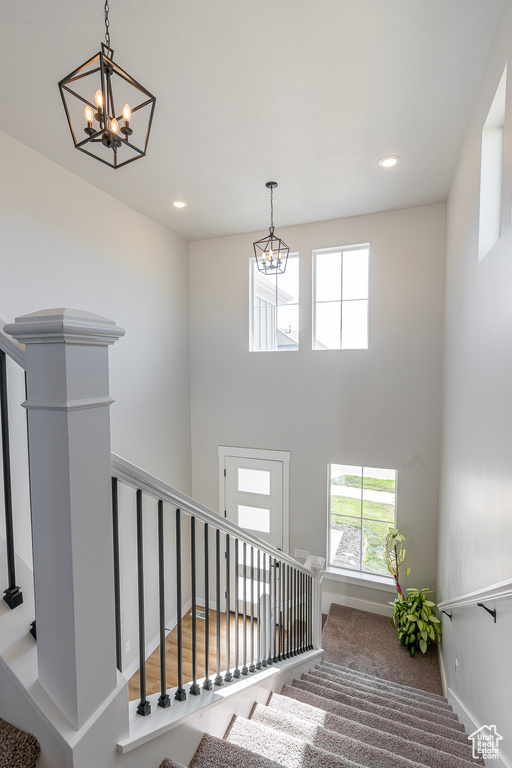 Stairs featuring a chandelier, recessed lighting, baseboards, and a high ceiling