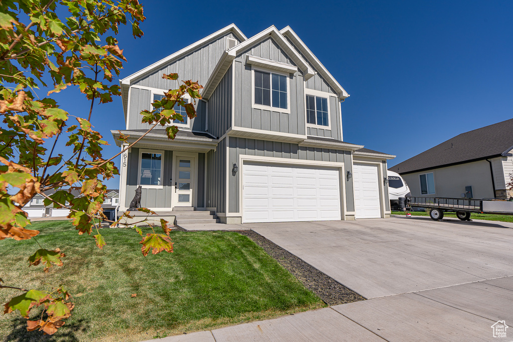 View of front of home featuring board and batten siding, an attached garage, driveway, and a front lawn