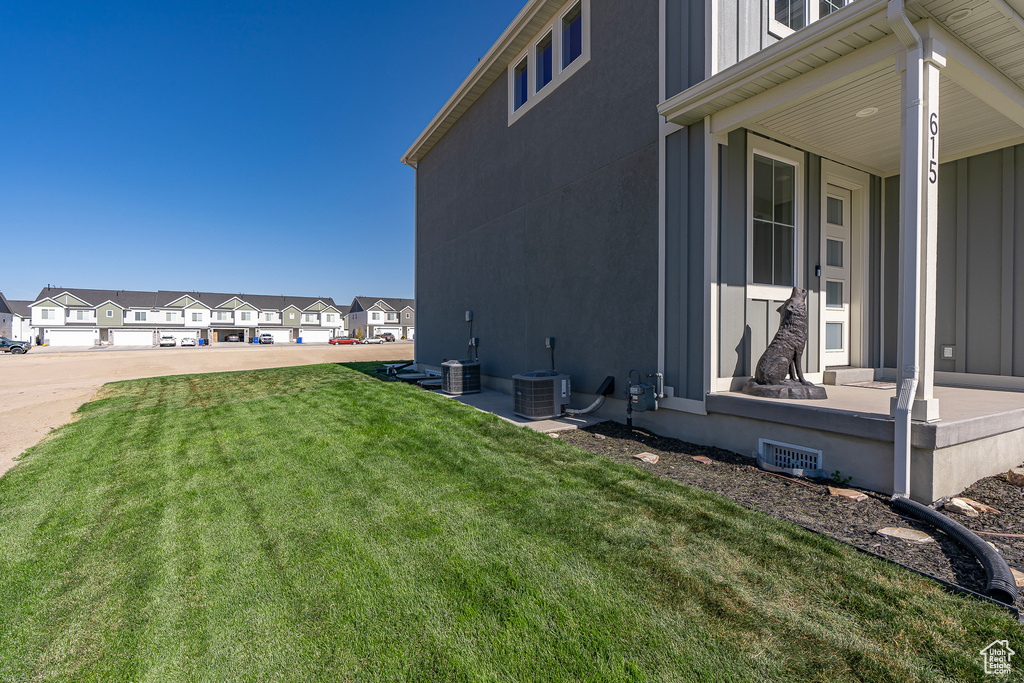 View of property exterior with a lawn, a residential view, board and batten siding, and central AC