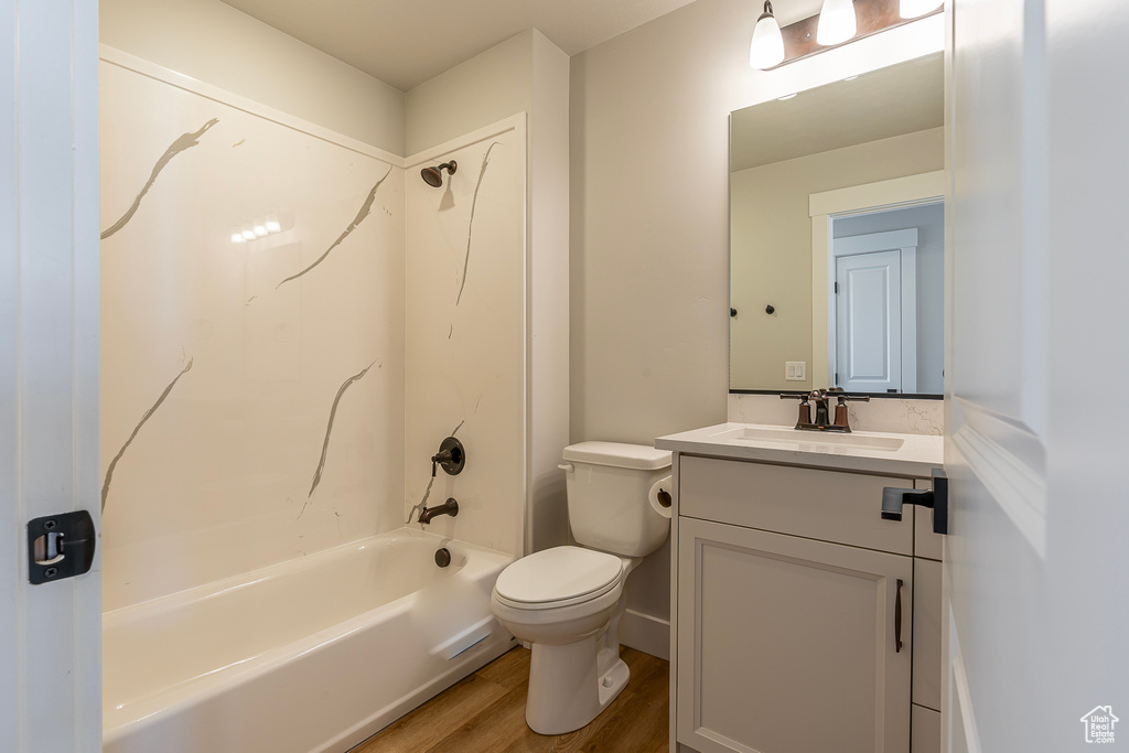 Bathroom featuring vanity, wood finished floors,  shower combination, and toilet