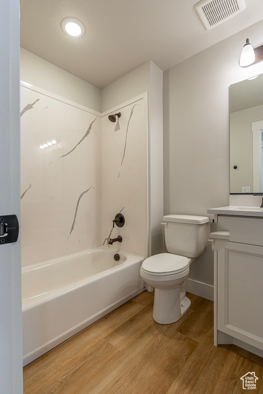 Full bathroom featuring toilet, vanity, bathtub / shower combination, and wood finished floors