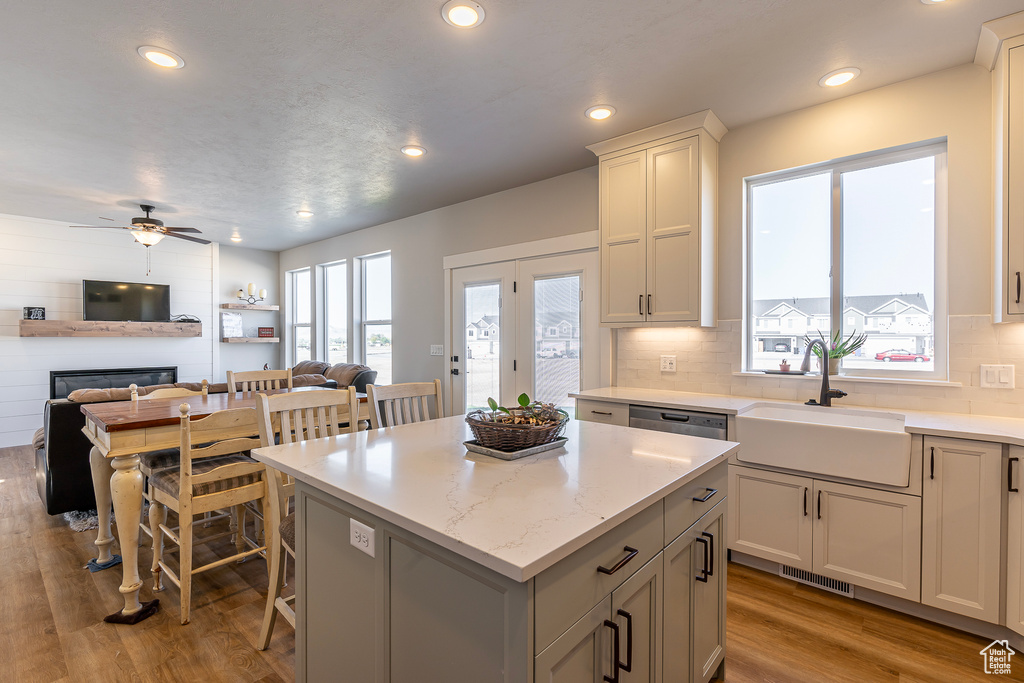 Kitchen with a sink, open floor plan, a kitchen island, light wood-style flooring, and a fireplace