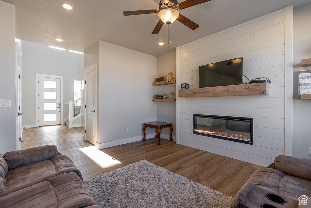 Living area with ceiling fan, a large fireplace, wood finished floors, baseboards, and recessed lighting