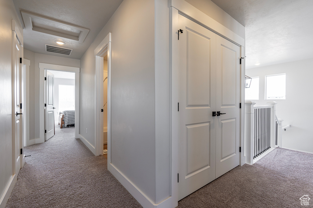Hallway with carpet, attic access, and baseboards