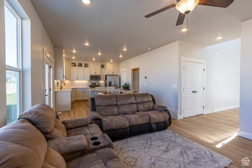 Living area featuring ceiling fan, light wood-style flooring, recessed lighting, and baseboards