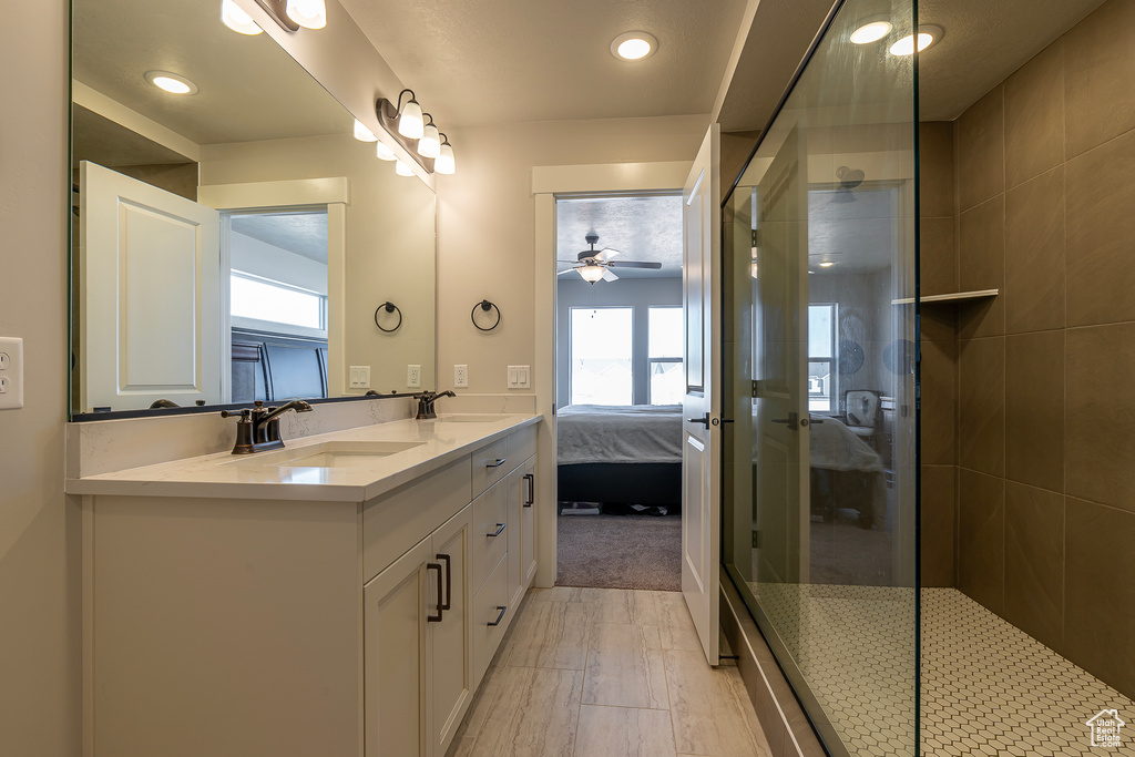 Full bathroom featuring ensuite bathroom, double vanity, ceiling fan, a walk in shower, and recessed lighting