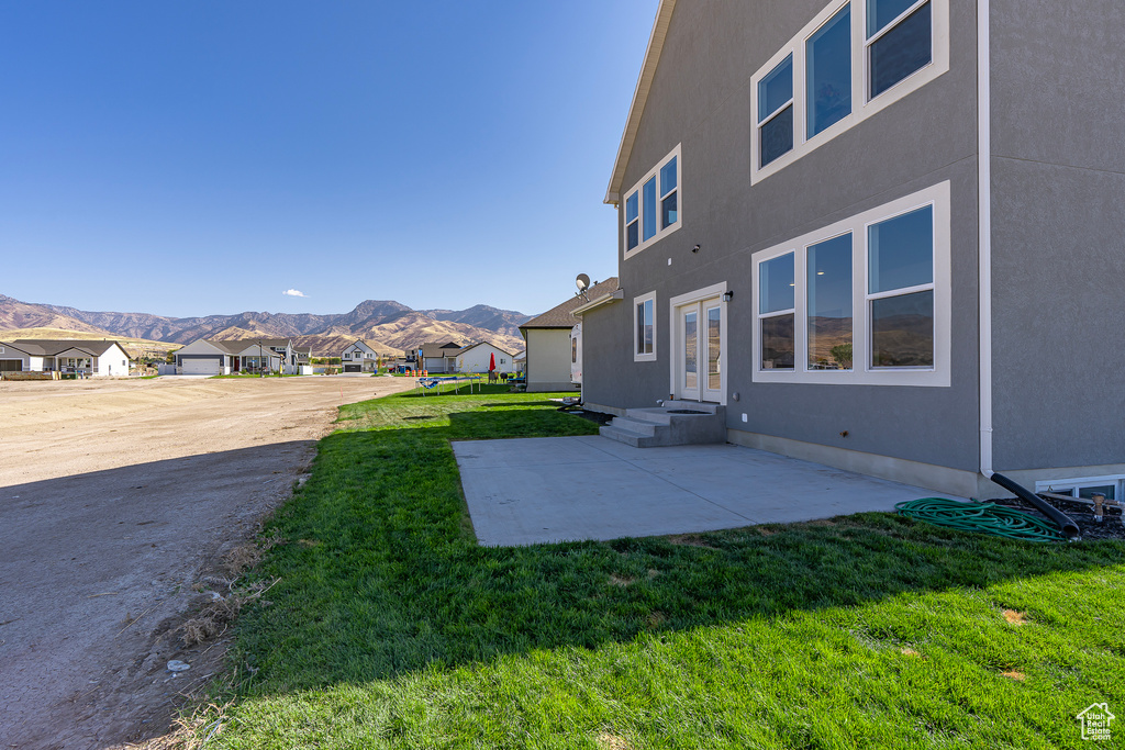 View of grassy yard with a mountain view, a patio area, and a residential view