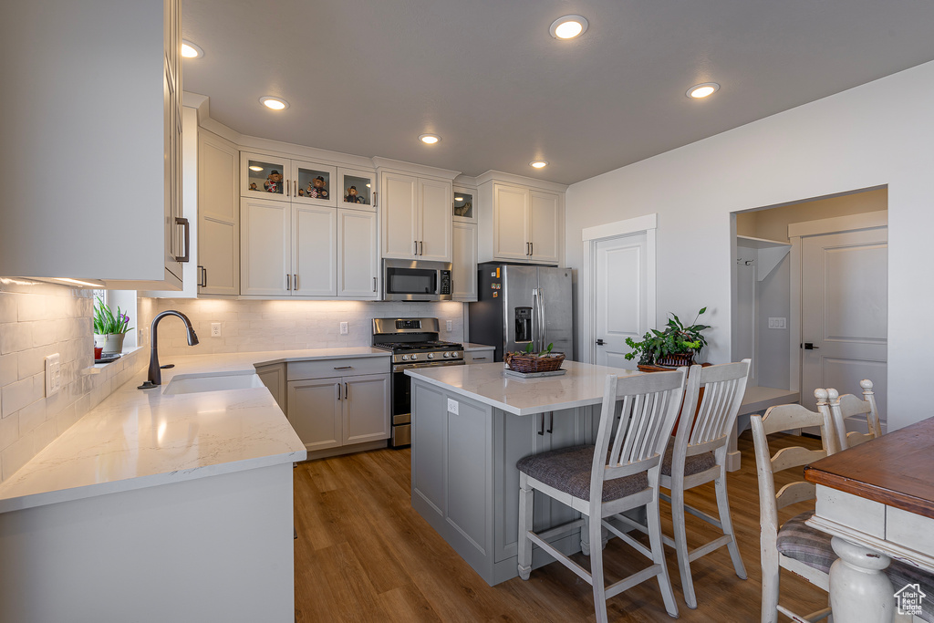Kitchen with stainless steel appliances, a sink, a breakfast bar, tasteful backsplash, and recessed lighting