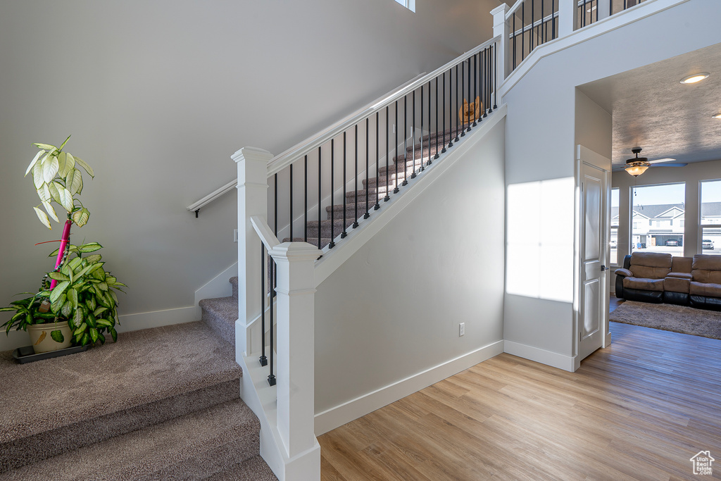 Stairs featuring baseboards, wood finished floors, and ceiling fan