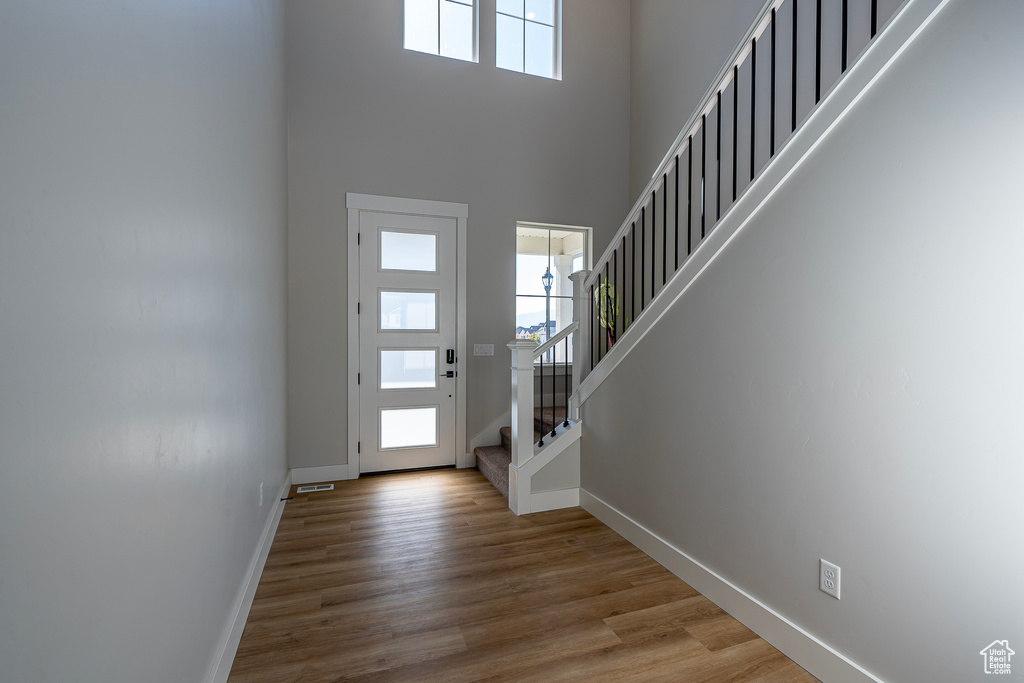 Entryway featuring stairway, baseboards, a high ceiling, and wood finished floors