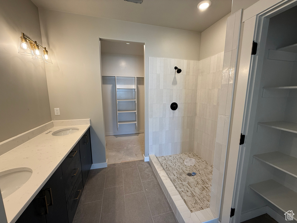 Bathroom featuring tiled shower, double vanity, tile patterned flooring, recessed lighting, and a spacious closet