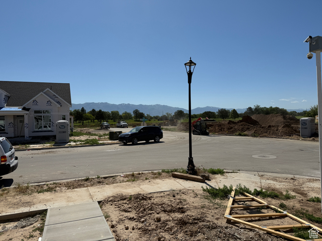 View of asphalt street featuring a mountain view and street lights