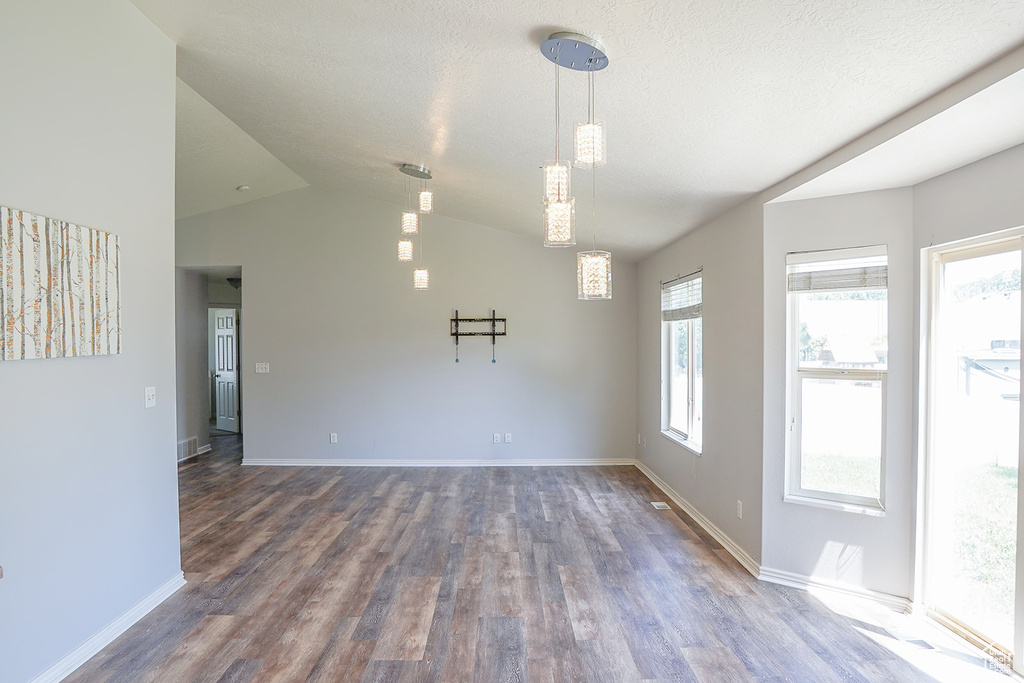 Spare room with wood finished floors, lofted ceiling, and baseboards
