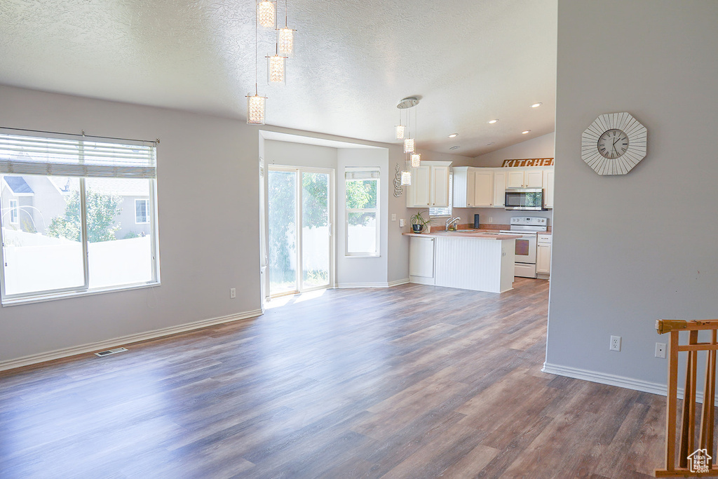 Unfurnished living room with dark wood finished floors, baseboards, vaulted ceiling, recessed lighting, and a sink