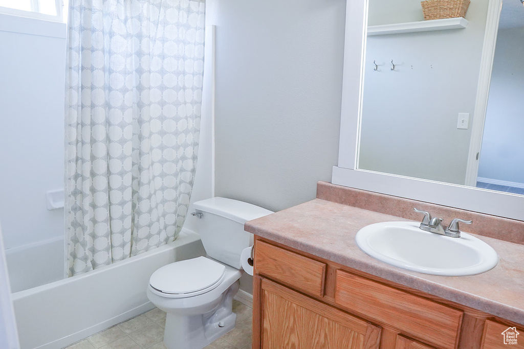 Full bathroom featuring vanity, shower / bath combo, toilet, and tile patterned flooring