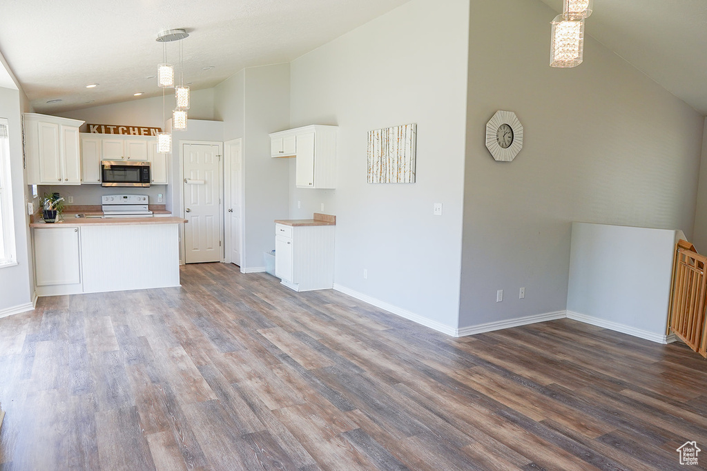 Kitchen featuring stainless steel microwave, white electric stove, dark wood finished floors, white cabinets, and baseboards