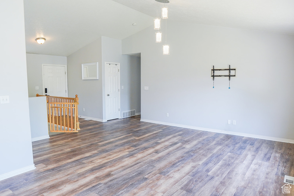 Empty room featuring baseboards, wood finished floors, and high vaulted ceiling