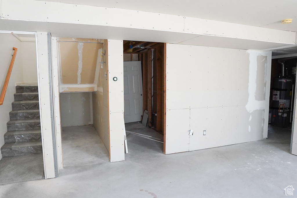 Unfinished below grade area featuring strapped water heater and stairway