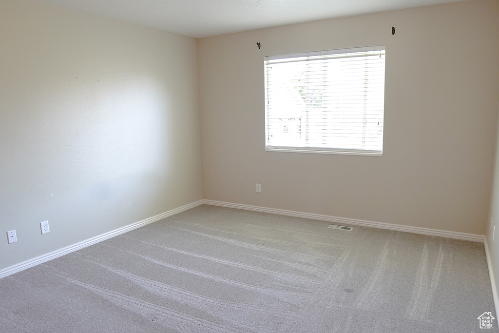 Empty room featuring light colored carpet and baseboards