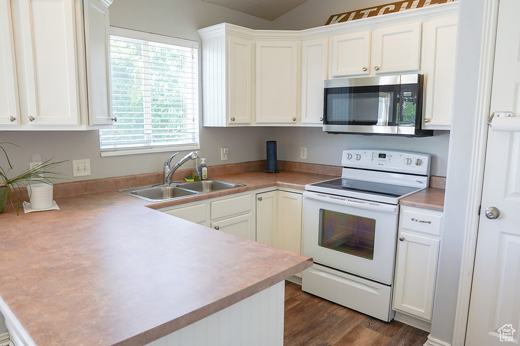 Kitchen with stainless steel microwave, white range with electric cooktop, a sink, a peninsula, and white cabinetry