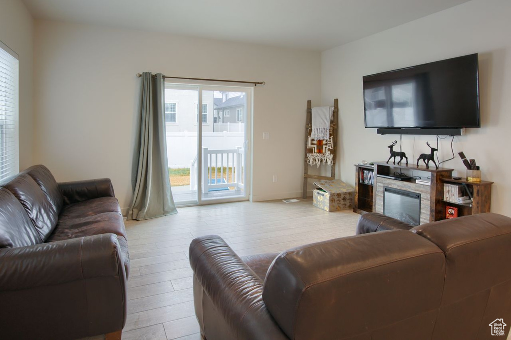 Living area with healthy amount of natural light, light wood finished floors, and a glass covered fireplace