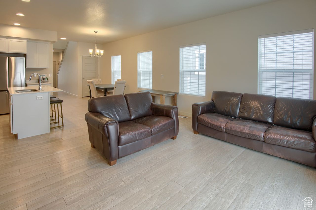 Living area with a chandelier, light wood-style flooring, recessed lighting, and baseboards