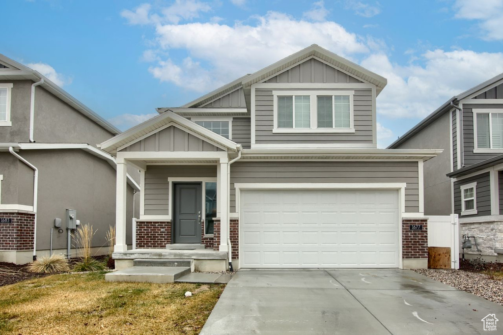 Craftsman inspired home with board and batten siding, brick siding, an attached garage, and driveway