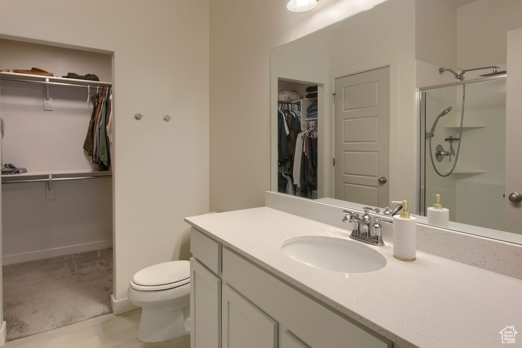 Bathroom featuring a spacious closet, a shower stall, vanity, and toilet