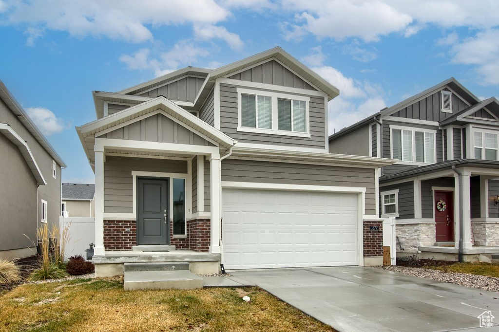 Craftsman-style home with board and batten siding, an attached garage, brick siding, and concrete driveway