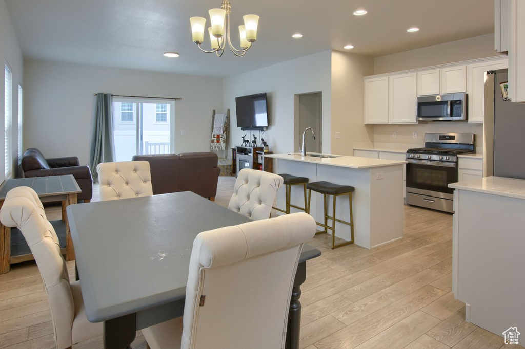 Dining space featuring healthy amount of natural light, light wood-style flooring, a chandelier, and recessed lighting