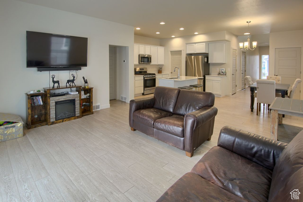 Living area featuring a chandelier, light wood-style floors, a fireplace, recessed lighting, and baseboards