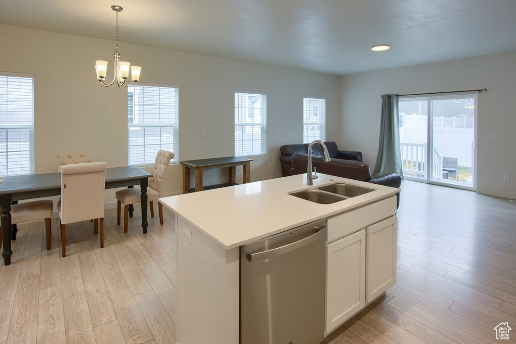 Kitchen with dishwasher, a sink, open floor plan, and light wood-style flooring