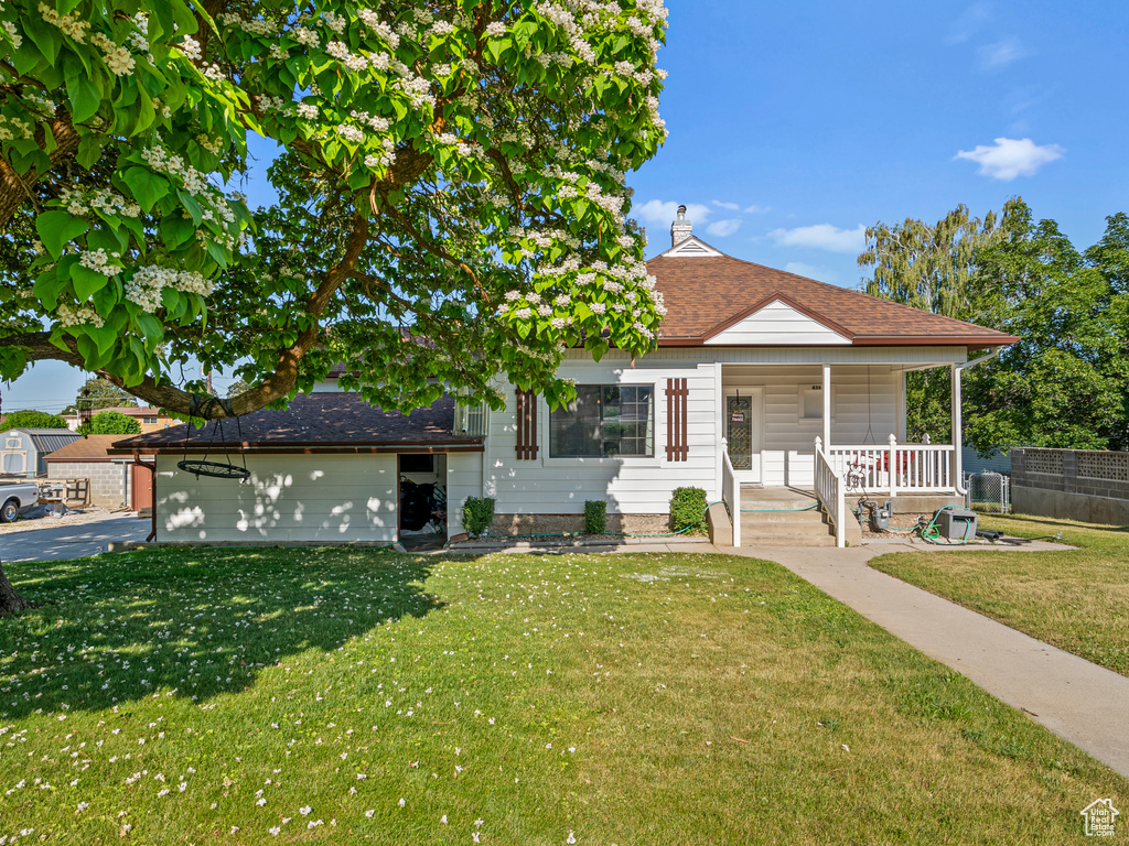 Bungalow with covered porch, an attached garage, a shingled roof, and a chimney