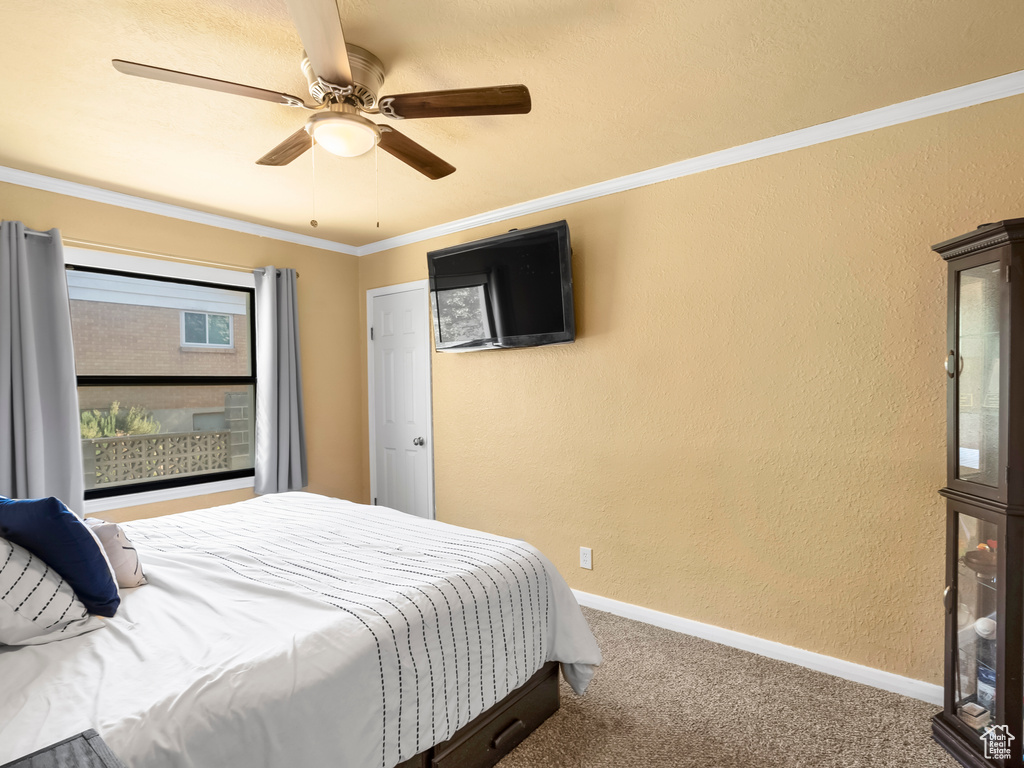 Bedroom featuring carpet, ceiling fan, a textured wall, and ornamental molding