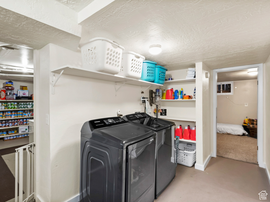 Washroom featuring washer and dryer, a textured ceiling, and light colored carpet