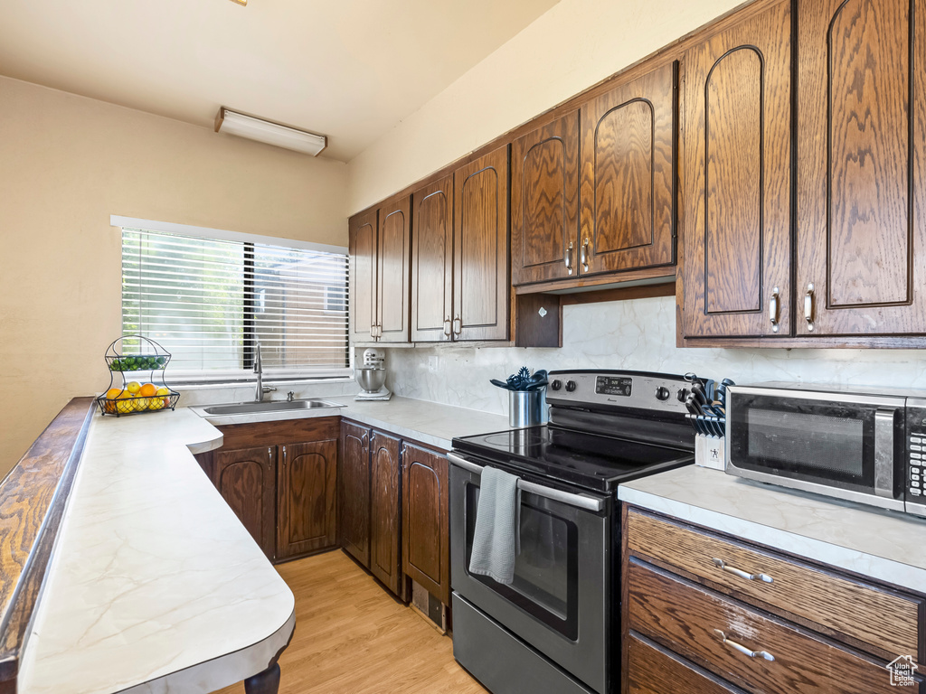 Kitchen with appliances with stainless steel finishes, light countertops, decorative backsplash, and light wood-type flooring