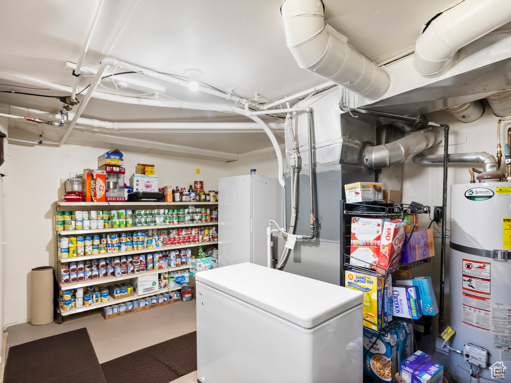 Basement with water heater and white fridge
