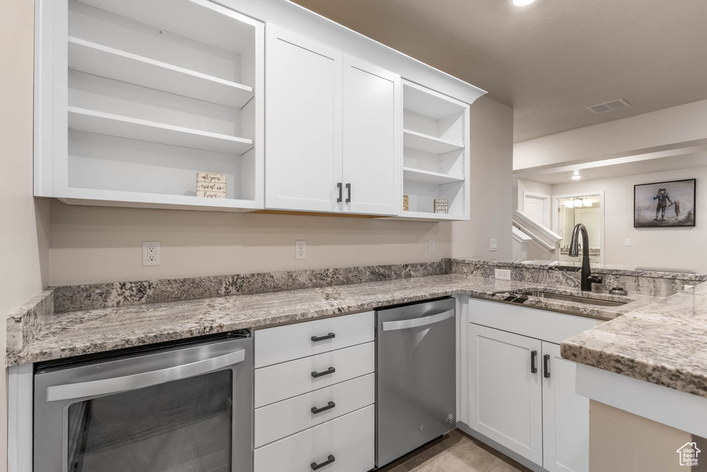 Kitchen with open shelves, dishwasher, beverage cooler, a sink, and white cabinetry