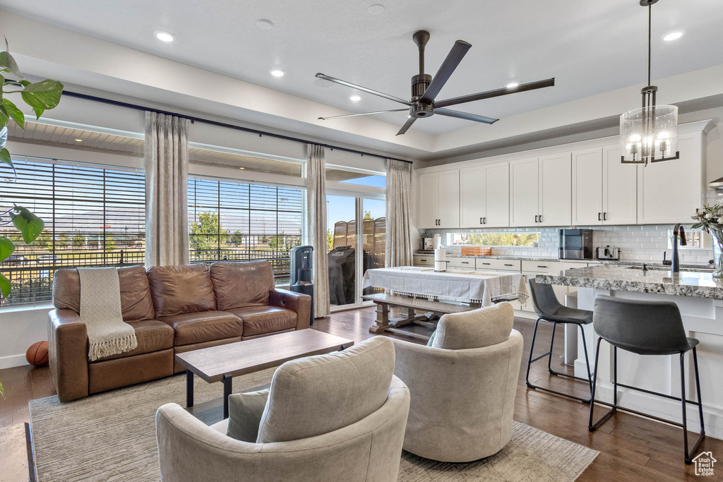 Living area with ceiling fan, healthy amount of natural light, dark wood-style floors, recessed lighting, and a chandelier