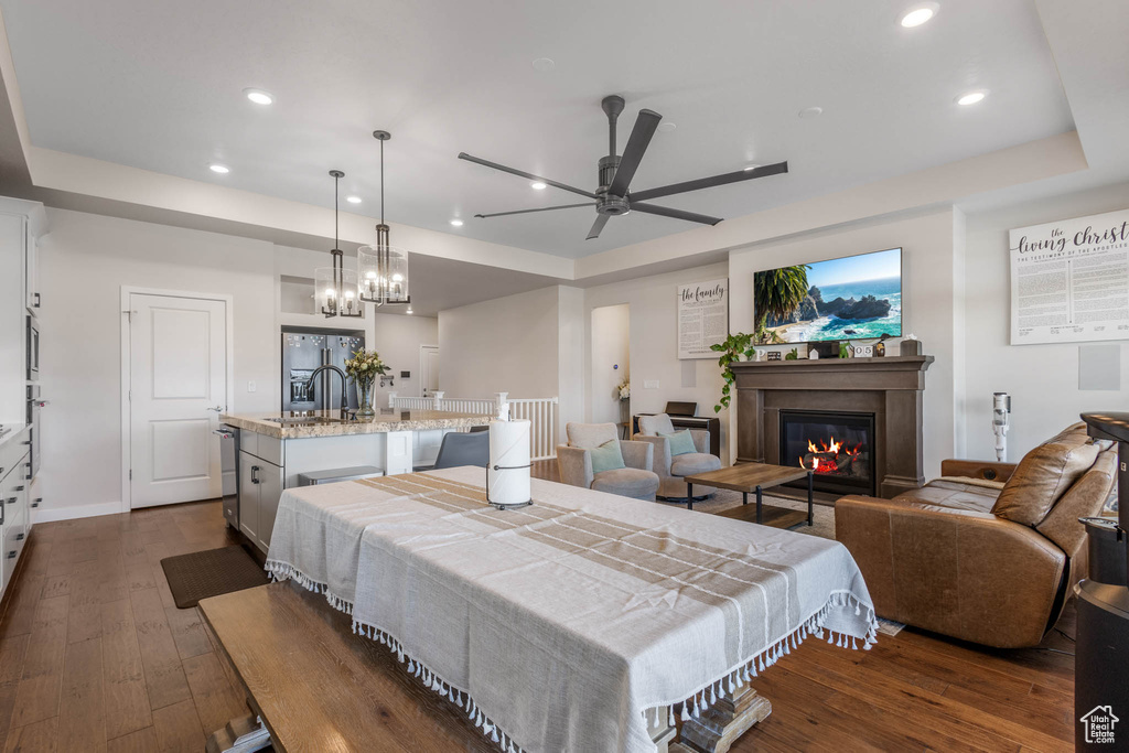 Dining area featuring a raised ceiling, ceiling fan, dark wood-type flooring, recessed lighting, and a glass covered fireplace