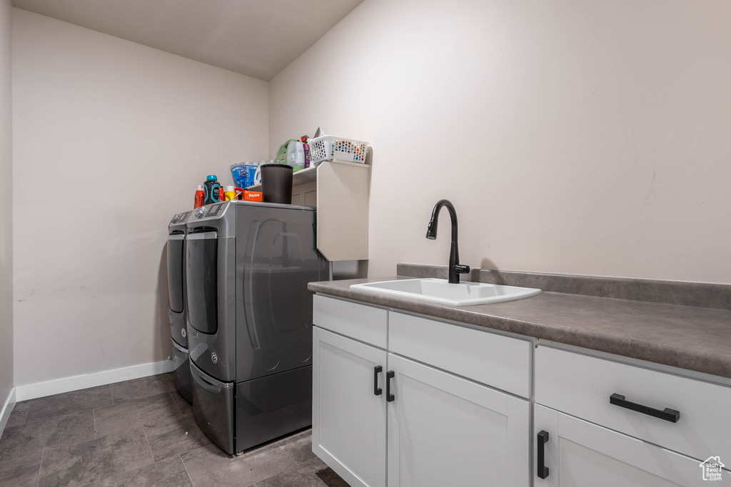 Laundry room with washer and clothes dryer, cabinet space, baseboards, and stone finish flooring