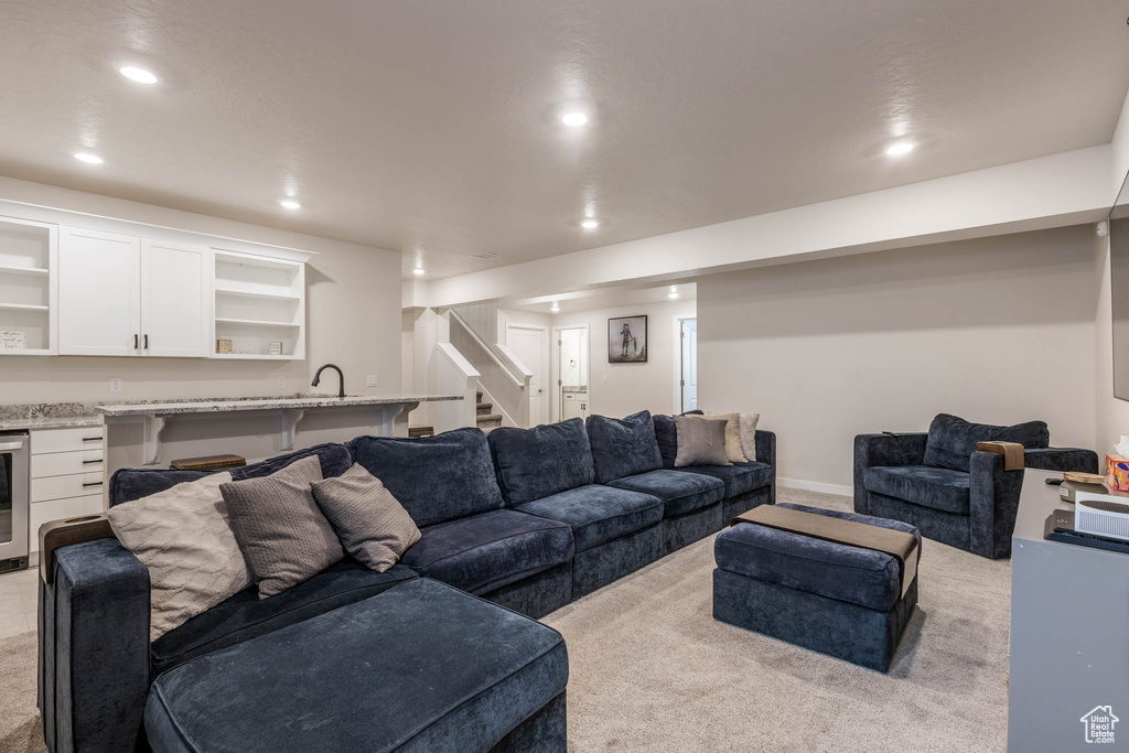 Carpeted living area with beverage cooler, recessed lighting, stairway, and bar