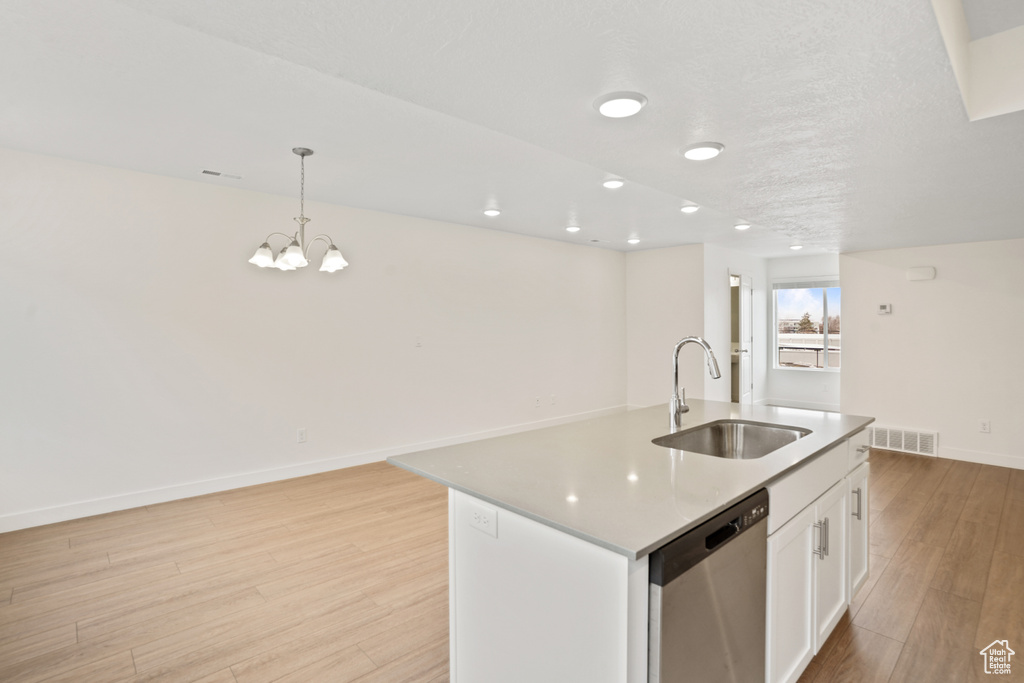 Kitchen with a sink, dishwasher, light wood-type flooring, a chandelier, and decorative light fixtures