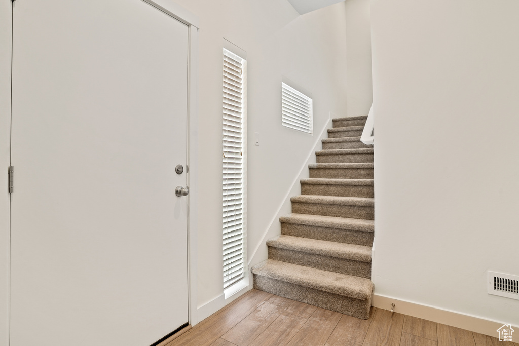 Foyer with light wood-type flooring, stairs, and baseboards